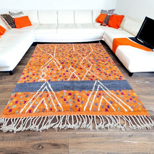 Full view of a handwoven coral geometric Azilal Moroccan rug with a dark gray band, and vibrant colored patterns.