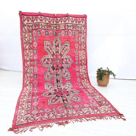 Full view of a pink floral handwoven wool Boujaad Moroccan rug with geometric motifs.